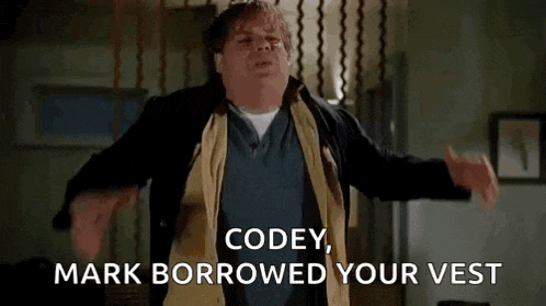 a man is standing in a room with his arms outstretched and says `` codey , mark borrowed your vest `` .