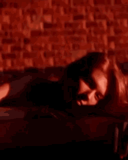 a woman is laying on a table in front of a brick wall at night .