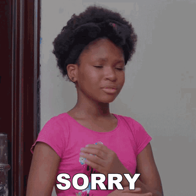 a girl in a pink shirt with the word sorry on her chest