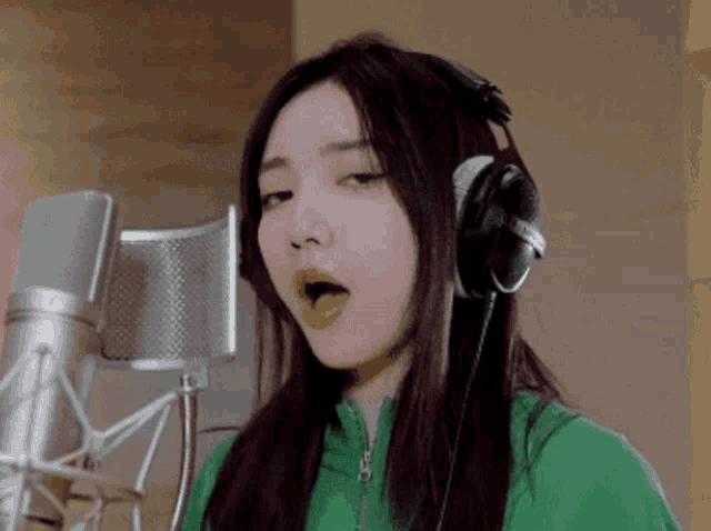 a woman singing into a microphone with headphones on