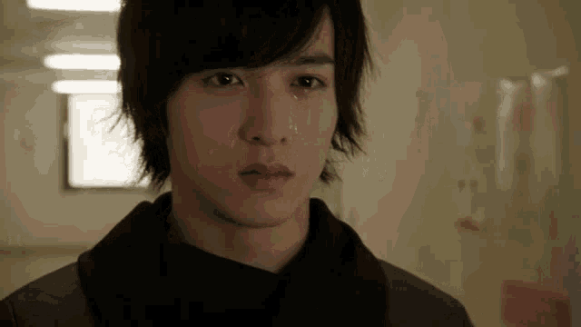 a close up of a young man 's face with tears coming out of his eyes