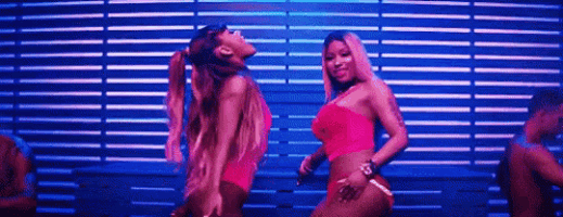 ariana grande and nicki minaj are dancing together in a club in front of a blue wall .