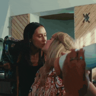 a woman kissing another woman on the cheek in a room