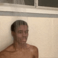 a shirtless man is taking a shower under a window .