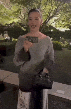 a woman holding a card that says bazaar