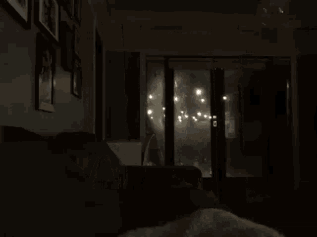 a person is looking out of a window at a rainy night .