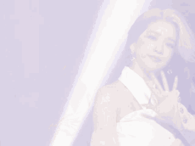 a woman in a white shirt and white gloves is waving her hand
