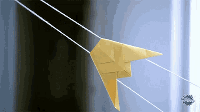 a yellow origami kite is flying in front of a sign that says el mundo on it