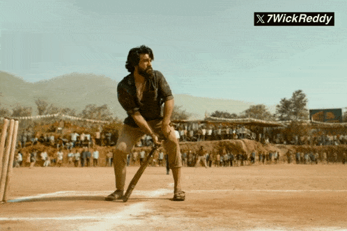 a man with a beard is holding a bat in front of a crowd and a sign that says " x7wickreddy "