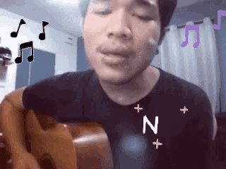 a man singing while holding a guitar with the letter n above his chest