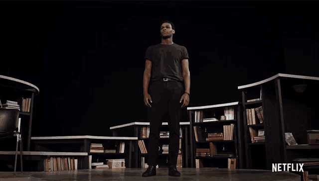 a man in a black shirt stands in a library with a netflix logo in the corner