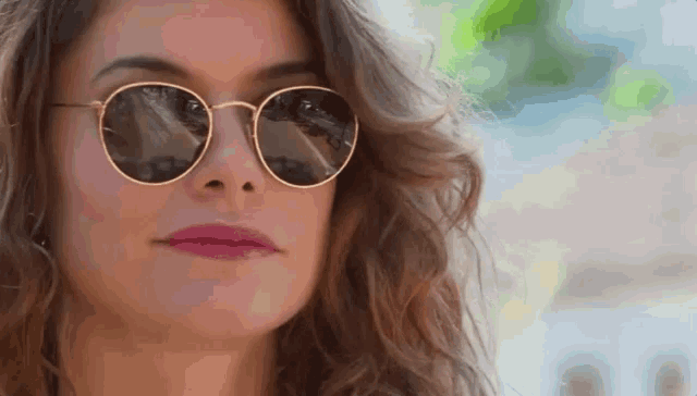 a close up of a woman wearing sunglasses and making a funny face .