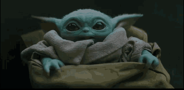 a baby yoda doll is sitting in a bag