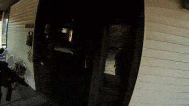 a person holding a gun in front of a house with a sign on the door that says ' a ' on it