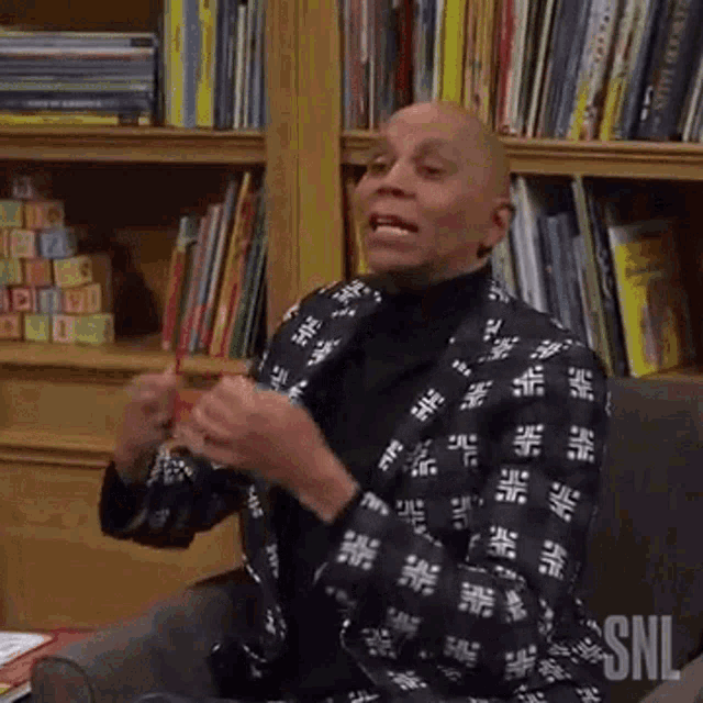 a man in a suit is sitting in a chair in front of a bookshelf in a library .