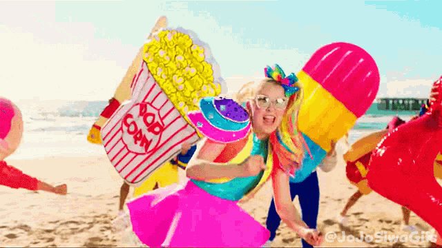 a girl holding a popcorn bucket on a beach