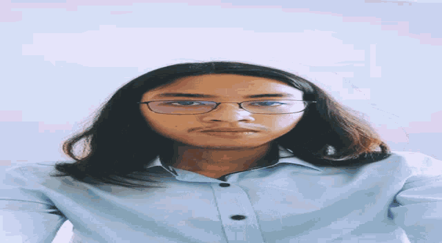 a woman wearing glasses and a blue shirt looks down