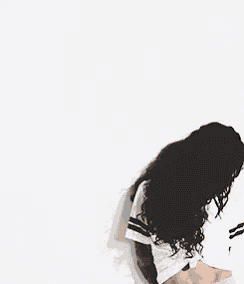 a woman with a tattoo on her arm is standing in front of a white wall wearing a crop top .