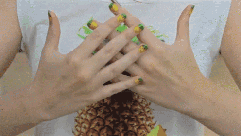 a woman with pineapple nails is wearing a white shirt with a pineapple on it