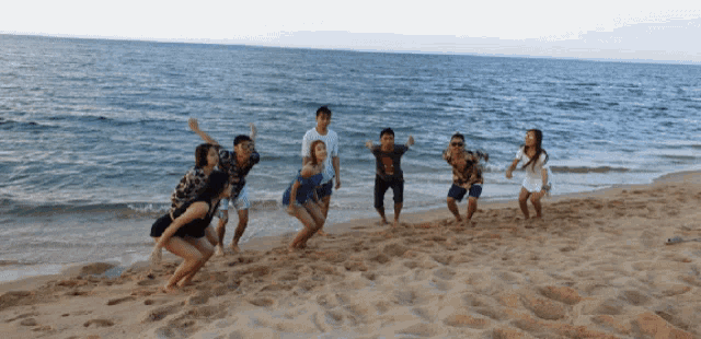 a group of people are standing on a sandy beach