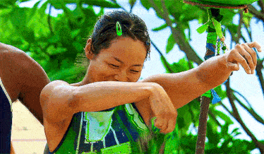 a woman in a green tank top is covering her face with her hand