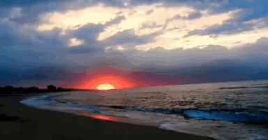a sunset over a body of water with waves coming in