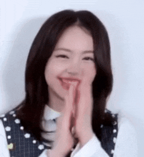 a young woman is smiling and clapping her hands .