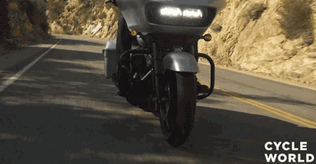 a harley davidson motorcycle is driving down a mountain road