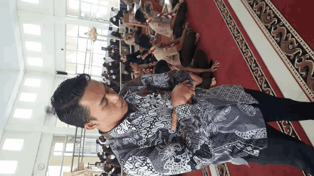 a man in a black and white shirt stands in front of a carpet that says ' nusantara '