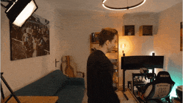 a man is standing in a room with a couch and a chair with the number 13 on it