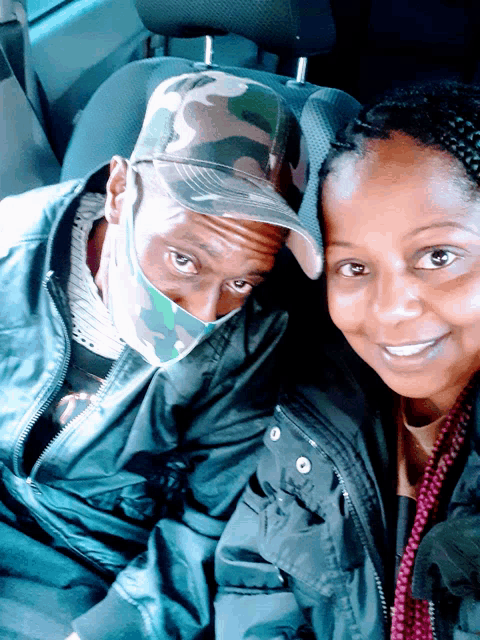 a man wearing a mask is sitting next to a woman wearing a jacket