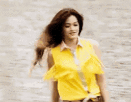 a woman in a yellow tank top is standing in the water .
