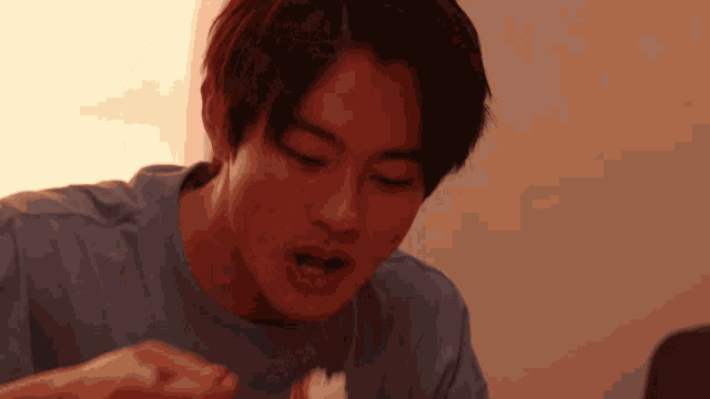 a young man in a blue shirt is eating a piece of food