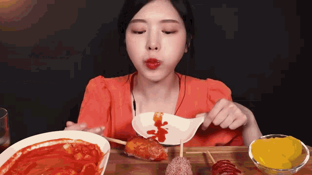 a woman is eating a plate of food with a spoon in her mouth