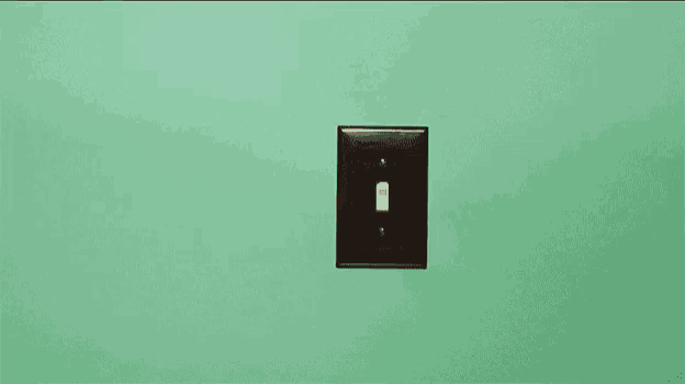 a woman with red nails is pressing a light switch on a green wall .