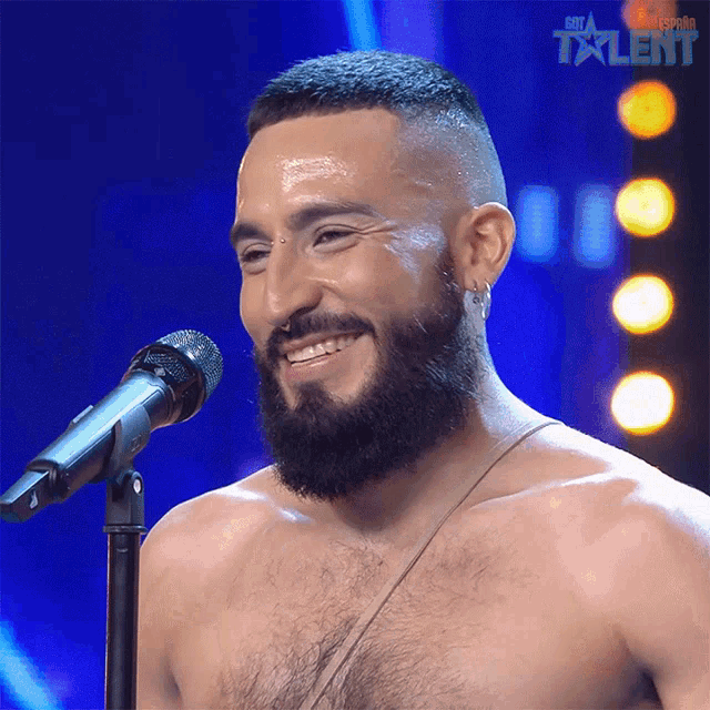 a shirtless man with a beard is singing into a microphone with the word talent on the bottom right
