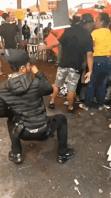 a man in a black jacket is squatting down in front of a crowd