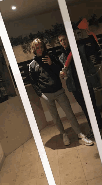 a man in a black jacket takes a picture of himself in a mirror