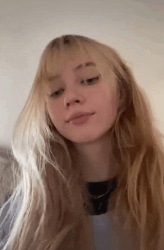 a close up of a girl with long blonde hair and bangs .