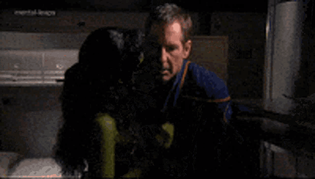 a man and a woman are hugging in a dark room with a sign that says mental illness in the background