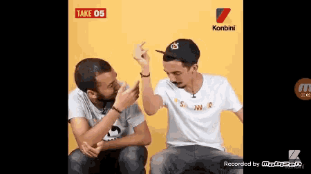 two men are sitting next to each other and one is wearing a white shirt that says ' snoop dogg ' on it