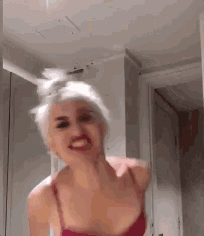 a woman in a red bra is making a funny face in a bathroom .