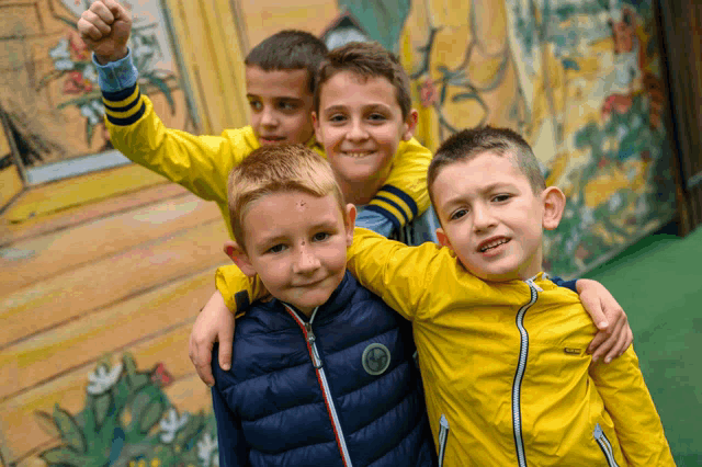 a group of young boys are posing for a picture and one of them is wearing a yellow jacket