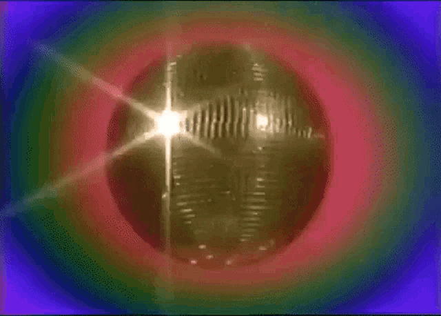 a disco ball is surrounded by a rainbow of lights .