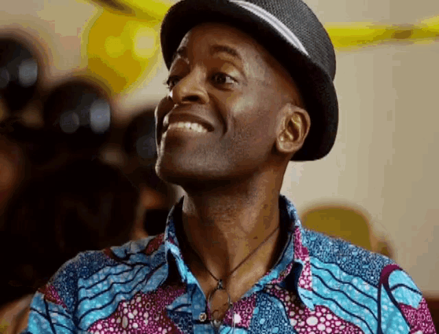 a man wearing a hat and a colorful shirt is smiling