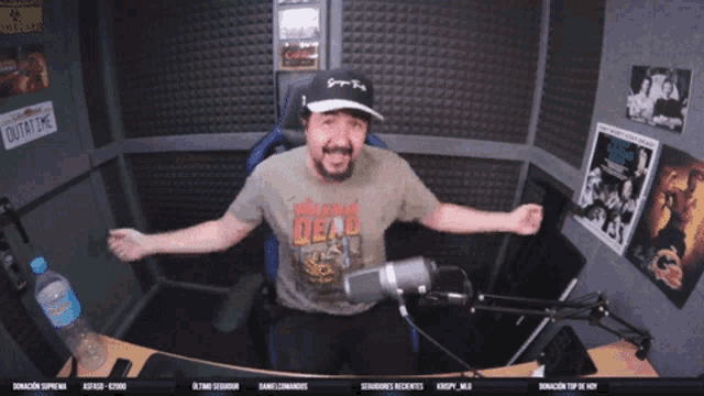 a man wearing a shirt that says walking dead is sitting in front of a microphone