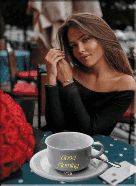 a woman is sitting at a table with a cup of coffee that says good morning