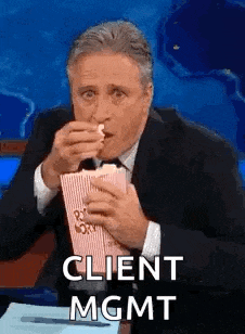 a man in a suit and tie is sitting at a table eating popcorn .