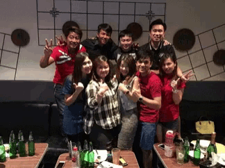 a group of people posing for a picture with bottles of beer on the table