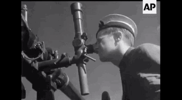a black and white photo of a man looking through a telescope with the letters ap on the bottom